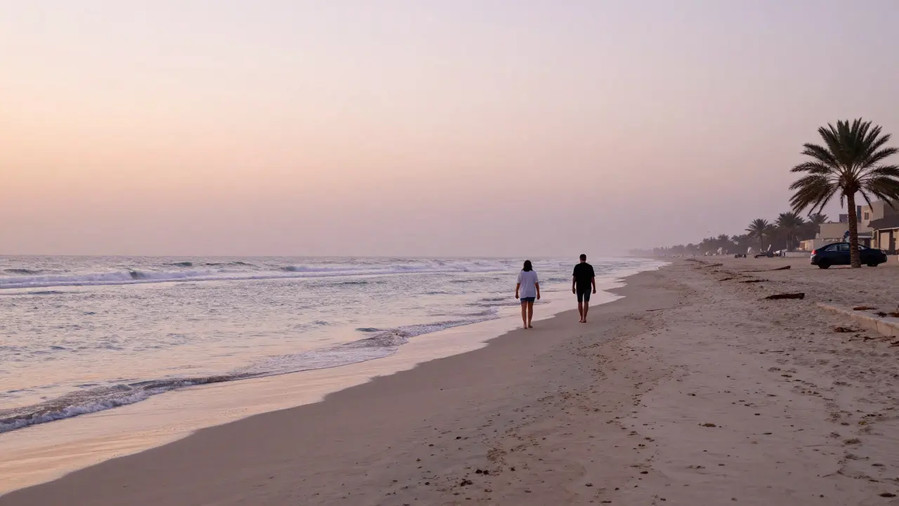 An empty beach at sunrise with two people walking near the water, far from crowds and cameras.
